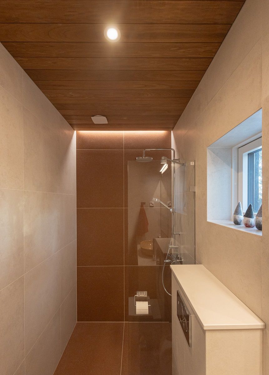 La parete posteriore della doccia è accentuata da una striscia LED uniforme e da un faretto a filo come illuminazione generale.